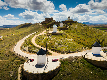 Scenic view from drone of ancient windmills and castle ruins atop Cerro Calderico ridge, Consuegra, Spainの写真素材