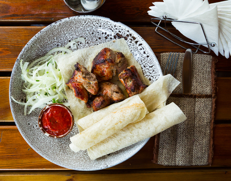 Traditional georgian dish shish kebab or shashlik, grilled pork meat served with onion and tomato sauce on flatbreadの写真素材