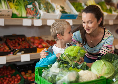 Little boy with his mother choosing fresh broccoli at vegetable department of supermarketの写真素材