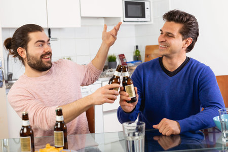 Best friends talk and drink beer in the kitchen