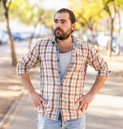 Portrait of an attractive man standing on street in a plaid shirtの写真素材