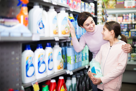 Young female customer with teenage daughter searching for cleaners in supermarketの写真素材