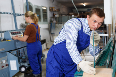Qualified workman working with glass in industrial workshop