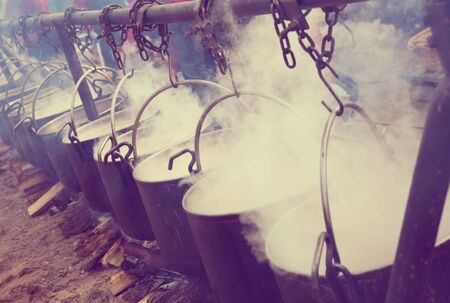 View of iron cauldrons for cooking outdoors in medieval style in open fireの写真素材