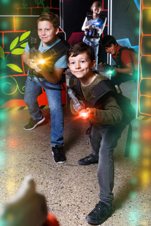 active boy aiming laser gun at other players during lasertag game in dark roomの写真素材
