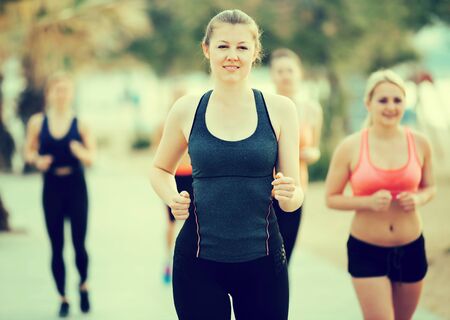 Young sporty women running along the embankment at sunny morningの写真素材