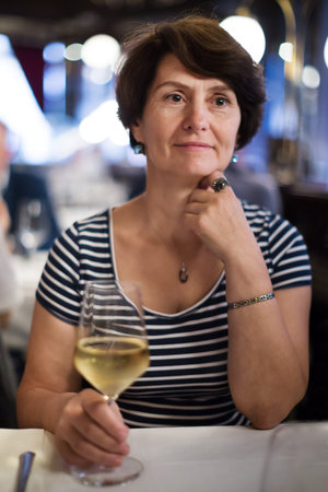 Elderly lonely woman at dinner at a comfortable restaurantの写真素材