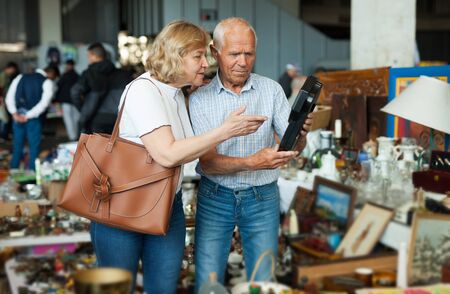 Mature man and his wife are visiting market of old thingsの写真素材