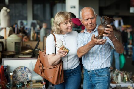Smiling mature spouses buying retro handicrafts on flea marketの写真素材