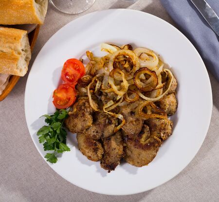 Tasty rabbit liver fried with onion garnished with fresh parsley and blanched cherry tomatoesの写真素材