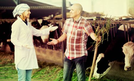 Portrait of positive worker and doctor working in cowhouseの写真素材