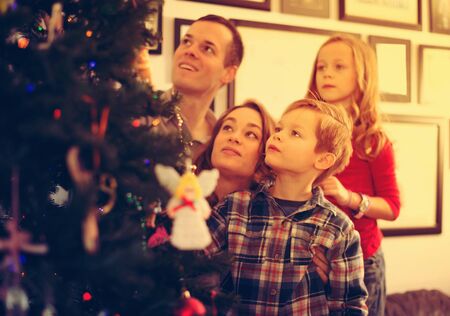 Smiling family of four preparing for Christmas together at homeの写真素材