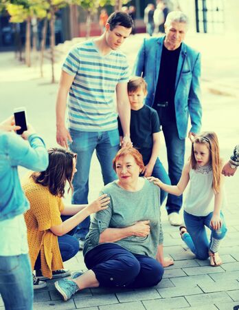 People of different ages helping grandmother with pain in heart in parkの写真素材