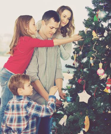 Young happy family decorating Christmas tree at homeの写真素材