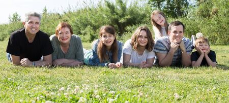 Happy family of different ages taking photos on the lawnの写真素材