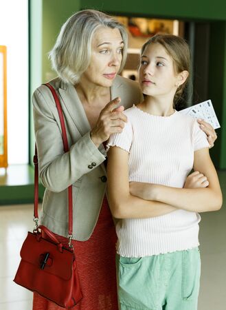 Intelligent female tutor helping tweenage girl exploring art pieces in art museumの写真素材