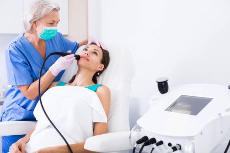 Young female getting facial cryolipolyse treatment in cosmetic cabinetの写真素材