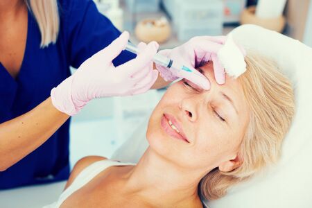 Portrait of woman during beauty facial injections in medical esthetic officeの写真素材
