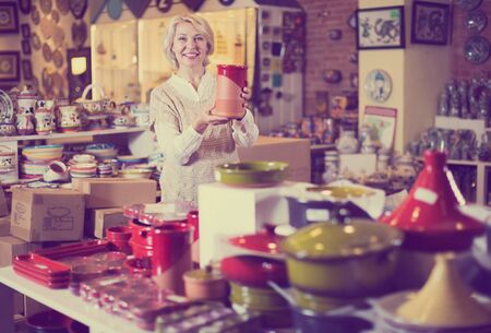 Elderly positive woman chooses ceramic ware in the cookware section at hypermarketの写真素材