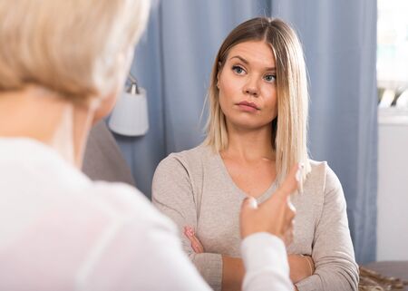 Frustrated middle-aged woman scolds a depressed adult daughterの写真素材