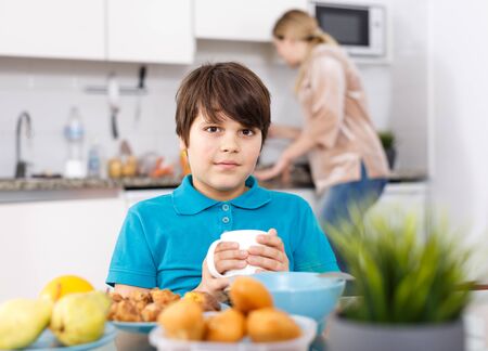 Portrait of tweenage boy having breakfast at kitchen at homeの写真素材