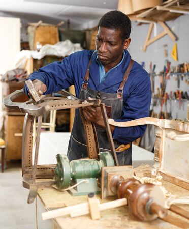 Portrait of craftsman restoring old chair in woodwork studioの写真素材