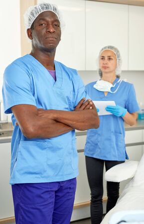 Cosmetician man before procedure in clinic of esthetic cosmetology, woman on backgroundの写真素材