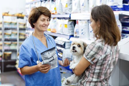 Mature woman veterinary consulting female client with cute havanese about pet dry feed in clinicの写真素材