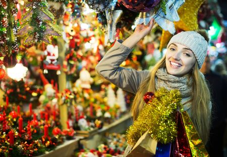 Happy girl in coat posing at Xmas market  in eveningの写真素材