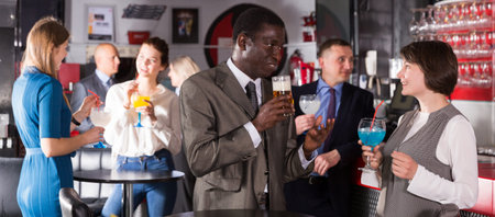 Respectable African man enjoying conversation with female colleague on corporate party in bar