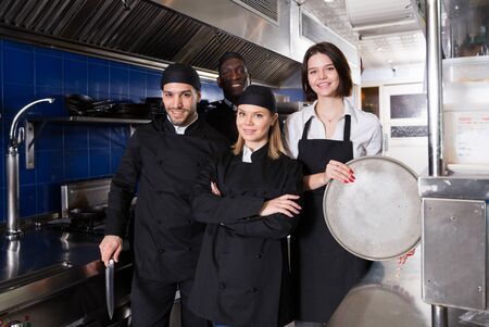 Portrait of command of cooks and woman waiter who are posing together on kitchen in restaurant.の写真素材
