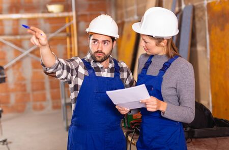 Workers man and woman discuss construction planの写真素材