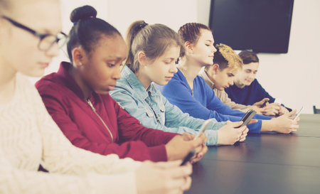 positive english classmates using their smartphones heavily during classes