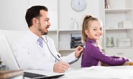 Little smiling girl visiting consultation with man doctor in hospitalの写真素材