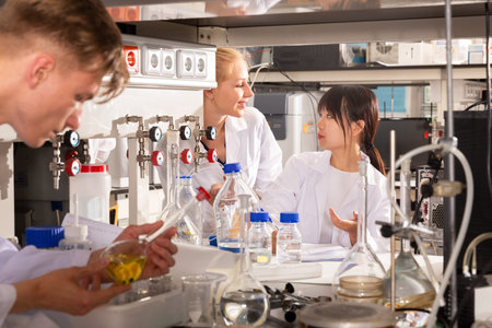 Two female students of Faculty of Chemistry performing experiments in university laboratory,...