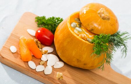Dietary squash soup in baked pumpkin bowl. Recipe: flesh of whole baked pumpkin pull out with spoon, puree in blender, add olive oil, salt, pepper. Pour in pumpkin. Serve with greens and pumpkin seedsの写真素材