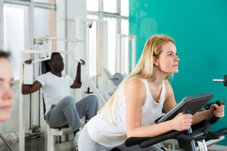 Group of people exercising with weight and on simulators in gym