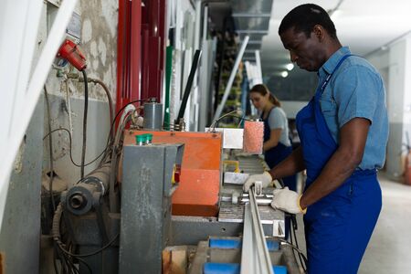 Male master is working with machine in the window workshop.の写真素材