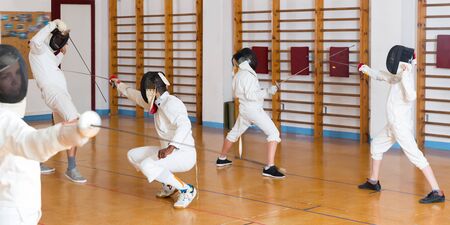 Friendly group  practicing effective fencing techniques in sparring in training roomの写真素材