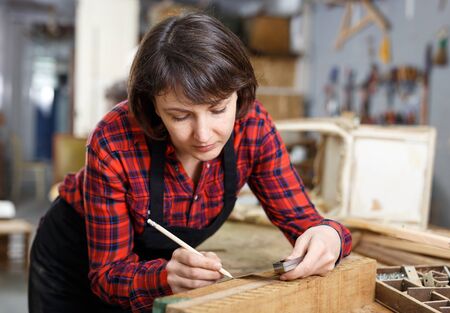 Female artisan in process of creation wooden furniture in workshopの写真素材
