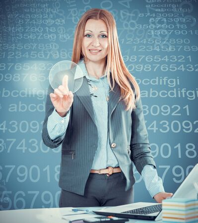 Woman touching screen on the background of modern glass buildingsの写真素材