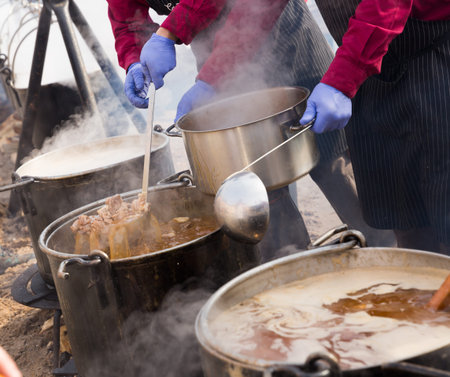 Traditional cooking in iron cauldrons hanging over open fire on medieval city festival
