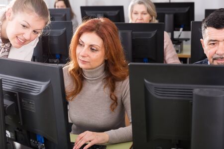 Young  businesswoman helping to coworkers, pointing at computer monitor in officeの写真素材