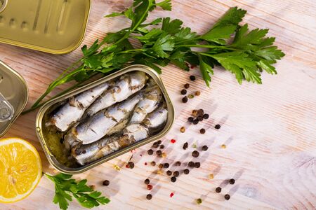 Open tin can of sprats, sardines in marinade of oil on wooden tabbleの写真素材
