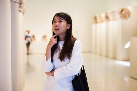 Thoughtful chinese girl  in  historical museum looking at antiquity art objectの写真素材