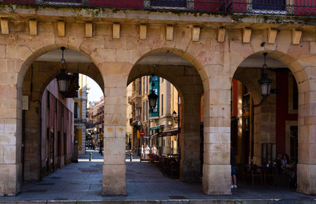 GIJON, SPAIN - JULY 15, 2019: View through archway of pedestrian street with people strolling in...