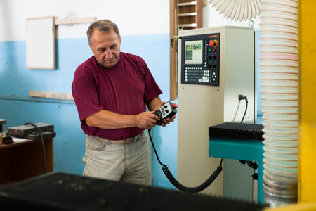 Elderly master manages 3d machine in factory
