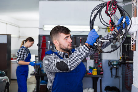 Male master is standing near her workplace and choosing instruments in the workshop