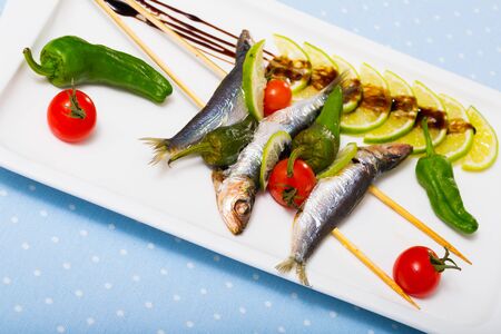 Seafood and vegetables skewers with balsamic paste. Grilled sprats, fresh tomatoes, green pepper, sliced limeの写真素材