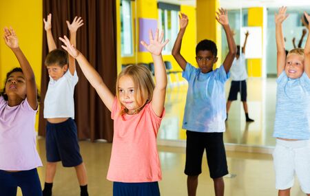 Group of schoolchildren exercising with female coach in choreography classの写真素材